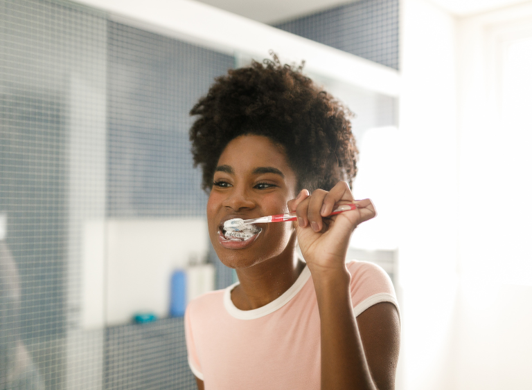 woman brushing her teeth to prevent gingivitis after visiting harwood dental practice